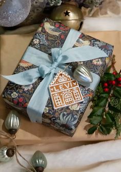 a present wrapped in wrapping paper with a gingerbread house on it next to christmas decorations