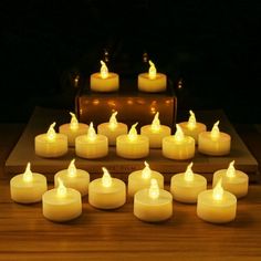 many lit candles sitting on top of a wooden table next to an old suitcase with the lid open