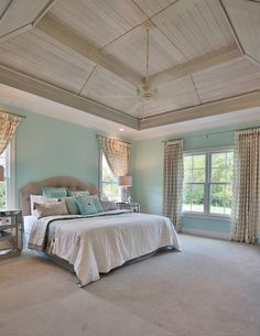 a bedroom with blue walls and carpeted flooring has a large bed in the center