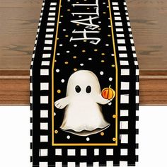 a black and white table runner with a ghost holding an orange ball in it's hand