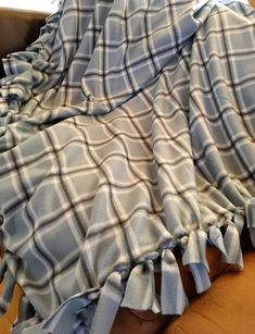 a woman laying on top of a brown couch under a blue and white plaid blanket