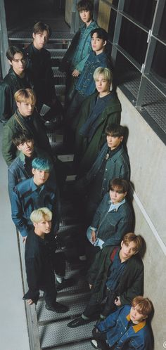 a group of young men standing on top of an escalator next to each other