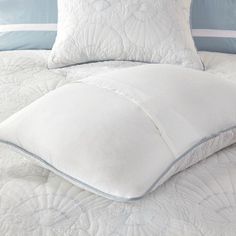 a bed with white pillows and blue trimmings on the headboard is shown