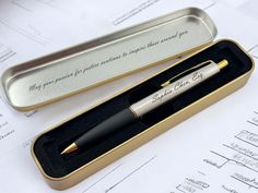 a pen sitting in a box on top of a table next to some papers with writing