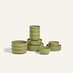 a stack of green bowls sitting next to each other on top of a white surface