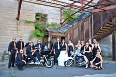 a group of people standing next to each other in front of a building with a motorcycle