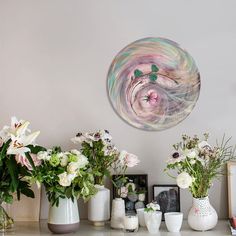 vases filled with flowers sitting on top of a table next to pictures and frames