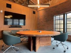 a conference room with chairs and a round table in front of a flat screen tv