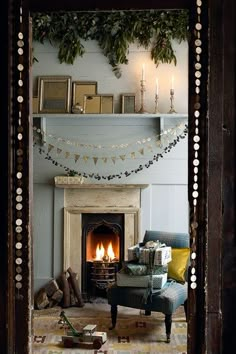 a living room filled with furniture and a fire place covered in christmas garlands next to a fireplace