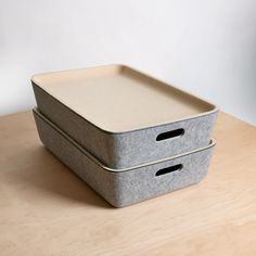 two gray boxes sitting on top of a wooden table