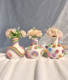 three vases with flowers in them sitting on a white cloth covered tablecloth next to each other