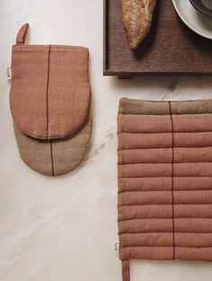 two pieces of bread sitting on top of a wooden cutting board next to an oven mitt