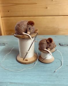 two stuffed mice sitting on top of a spool of thread