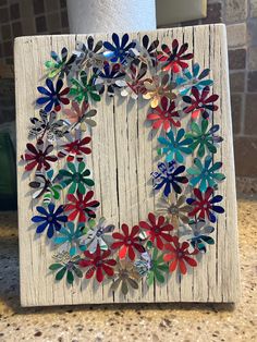 a wreath made out of paper flowers on a wooden board