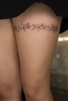 the back of a woman's thigh with tattoos on it and flowers in the middle