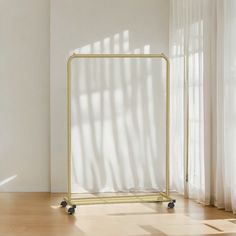 a white room with a gold frame on the floor and a wooden floor next to it