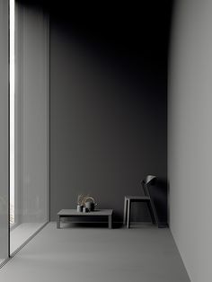 a black and white photo of a room with a chair, table and glass door