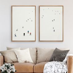 two framed pictures hang on the wall above a couch