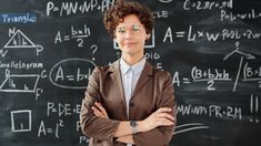 a woman standing in front of a blackboard with writing on it and wearing glasses