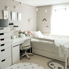 a bedroom with a bed, desk and chair next to a white dresser in front of a window