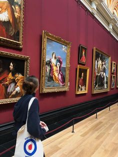 a woman is looking at paintings on the wall