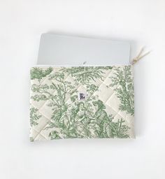 a green and white floral print envelope on a white surface with a string attached to it