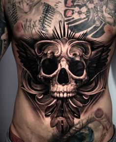 a man with tattoos on his stomach has a skull and wings tattoo on his chest