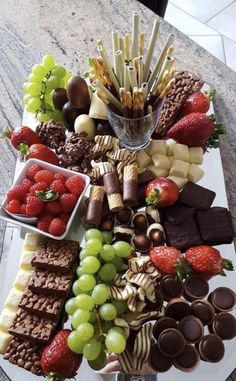 a platter filled with chocolates, strawberries, grapes and other snacks on top of a table