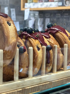 doughnuts with chocolate and blueberries are on display in a bakery shop window