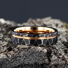 a black and gold wedding band with an animal print pattern on the inside, sitting on top of a rock