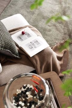 a glass bowl filled with rocks on top of a wooden table next to a book