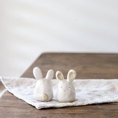 two ceramic rabbits sitting on top of a white towel