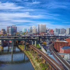 a view of a city with train tracks and bridge over the river in front of it