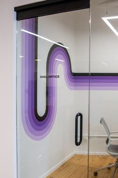 an office with a glass wall and chair in front of the door that has purple lines painted on it