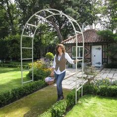 a woman standing in the middle of a garden with a white trellis around her