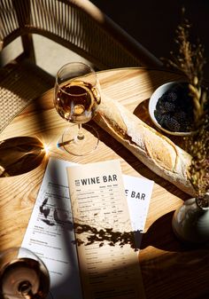 a wine bar menu and glass of wine on a wooden table with wicker chairs