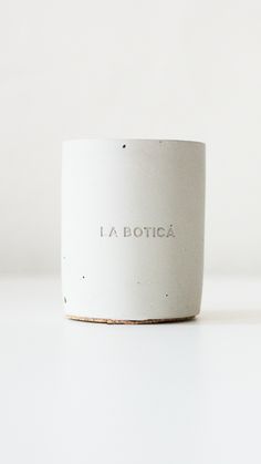 a white cup with the word la botica printed on it