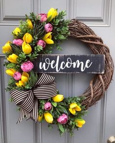 a welcome wreath with yellow and pink tulips hanging on the front door,