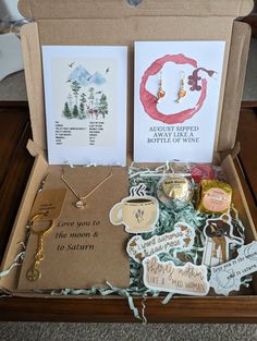 an open box filled with lots of different items on top of a wooden table next to cards and magnets