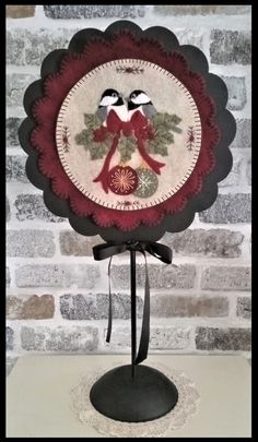 two birds sitting on top of a red and white plate with black ribbon around it