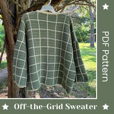 a green sweater hanging from a tree in the grass with stars around it and text overlay that reads, off the grid sweater