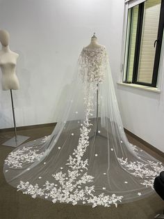 a wedding dress on display in front of a mannequin wearing a veil with white flowers