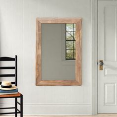 a wooden chair sitting in front of a white door with a mirror on the wall