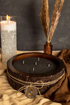 a wooden clock sitting on top of a table next to a candle and some feathers