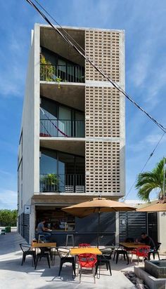 an apartment building with tables and chairs outside