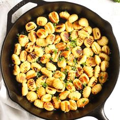 a skillet filled with shells and broccoli on top of a white cloth