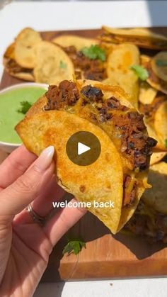 a person is holding up a tortilla in front of some other food on a cutting board