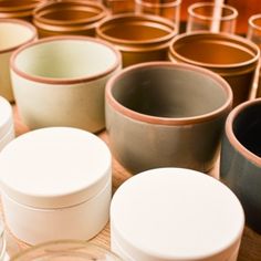 there are many pots and containers on the table together, all lined up in rows