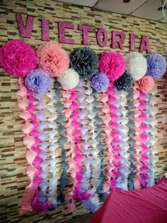 the wall is decorated with tissue pom poms