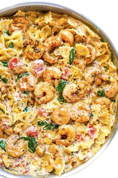 pasta with shrimp and spinach in a pan on a white table top, ready to be eaten